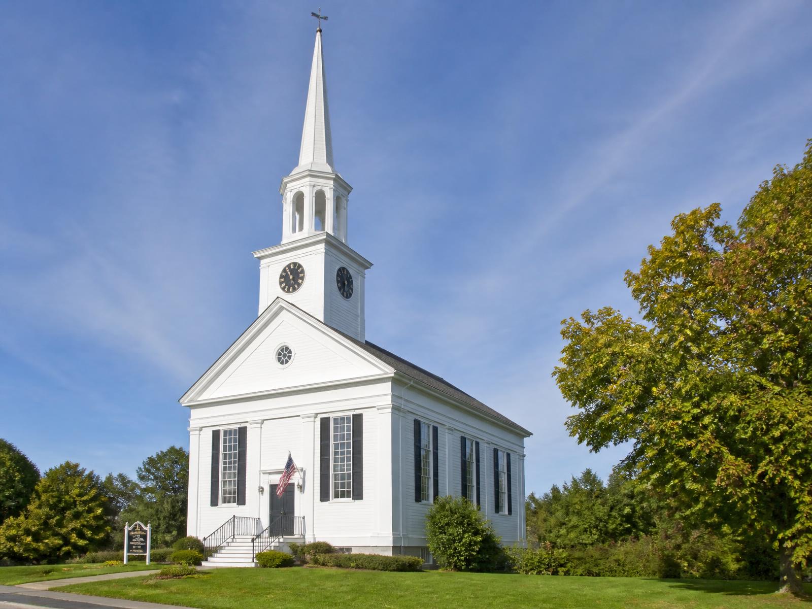 White clapboard church with a tall steeple on a clear morning
