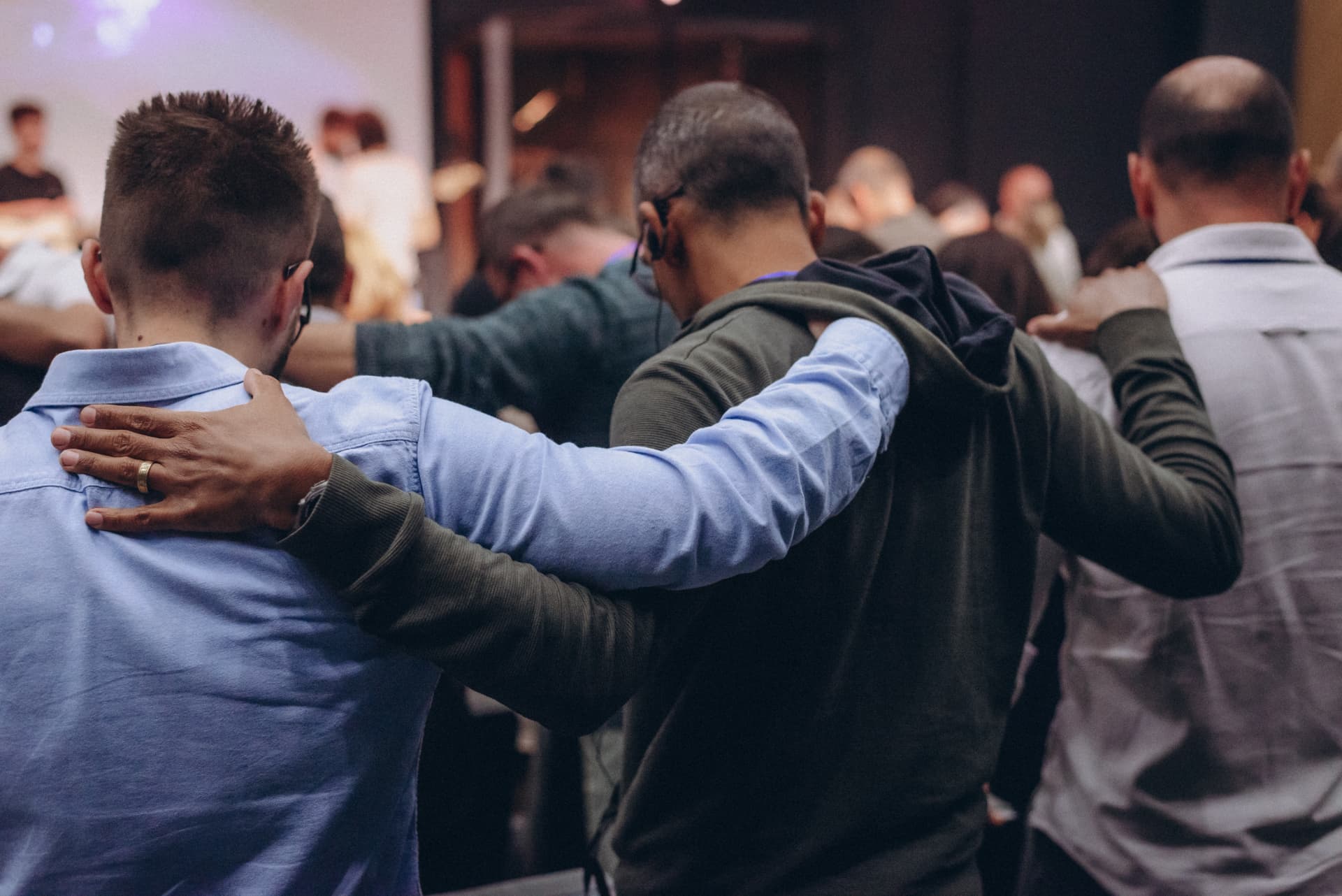 Congregation members praying together arm in arm